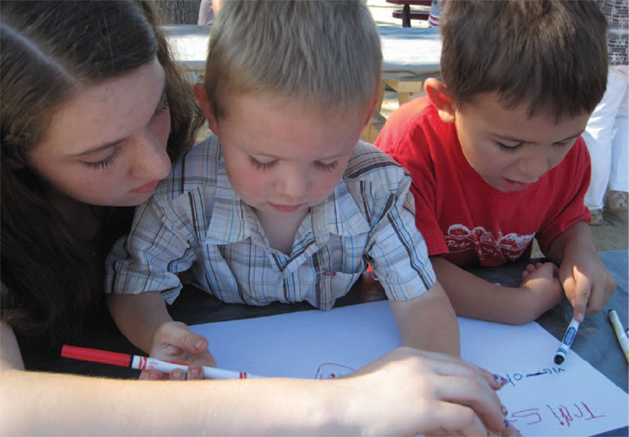 Eighth-grader Paige works with her kindergarten buddies, Tristan and Victor, on their letters. (Photo courtesy the author.) 